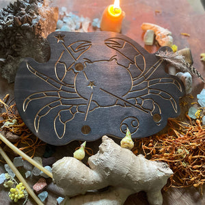 cancer astrology wooden art therapy project surrounded by dried flowers, crystals, and candles