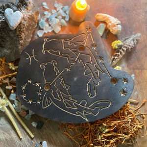 pisces astrology wooden art therapy project surrounded by dried flowers, crystals, and candles