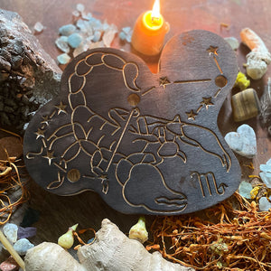 scorpio astrology wooden art therapy project surrounded by dried flowers, crystals, and candles