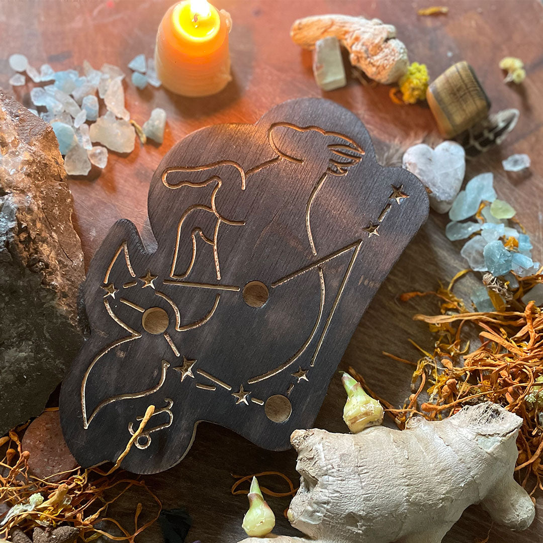 capricorn astrology wooden art therapy project surrounded by dried flowers, crystals, and candles