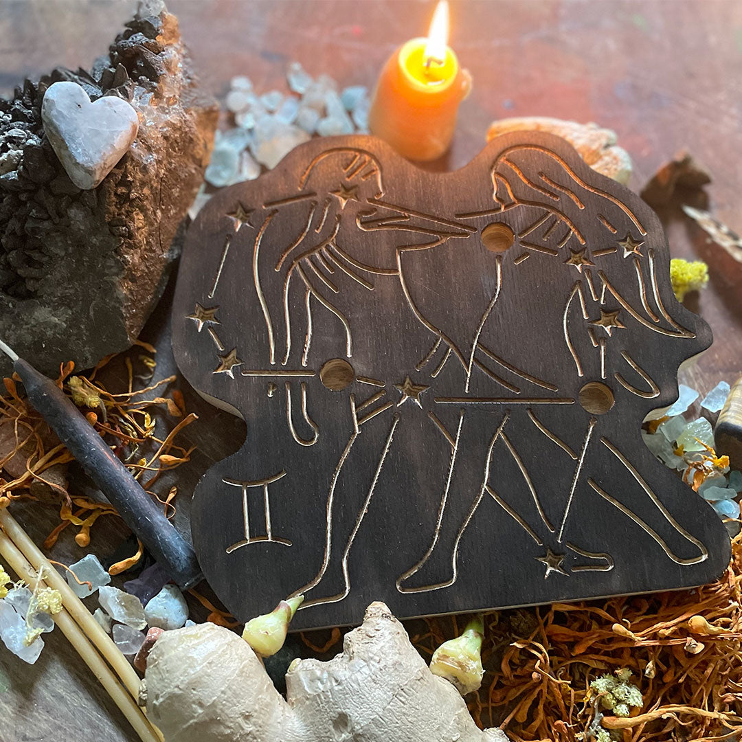 gemini astrology wooden art therapy project surrounded by dried flowers, crystals, and candles