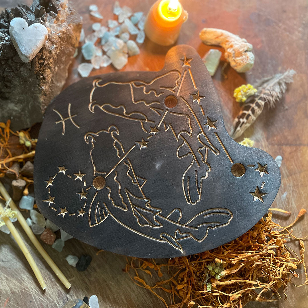 pisces astrology wooden art therapy project surrounded by dried flowers, crystals, and candles