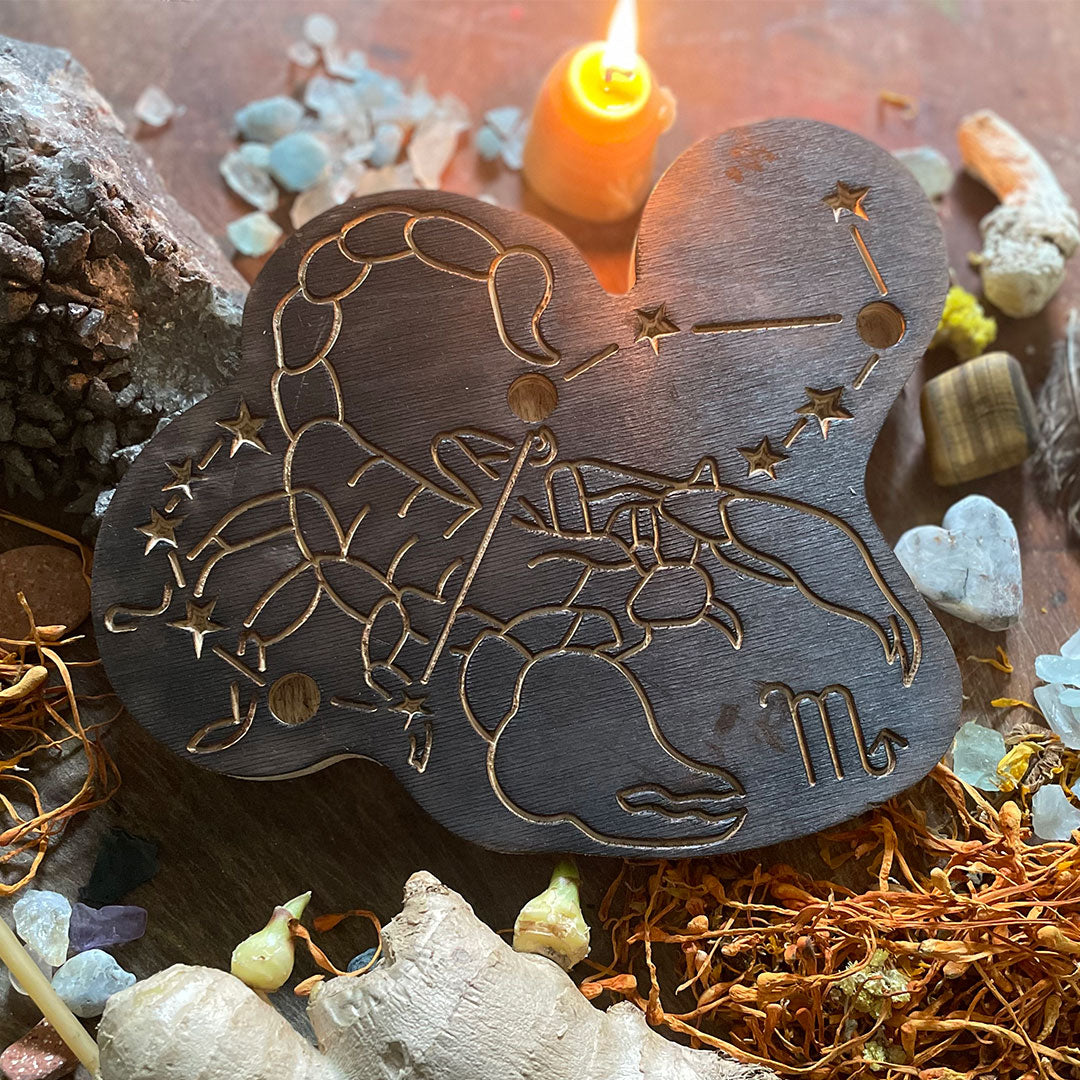 scorpio astrology wooden art therapy project surrounded by dried flowers, crystals, and candles