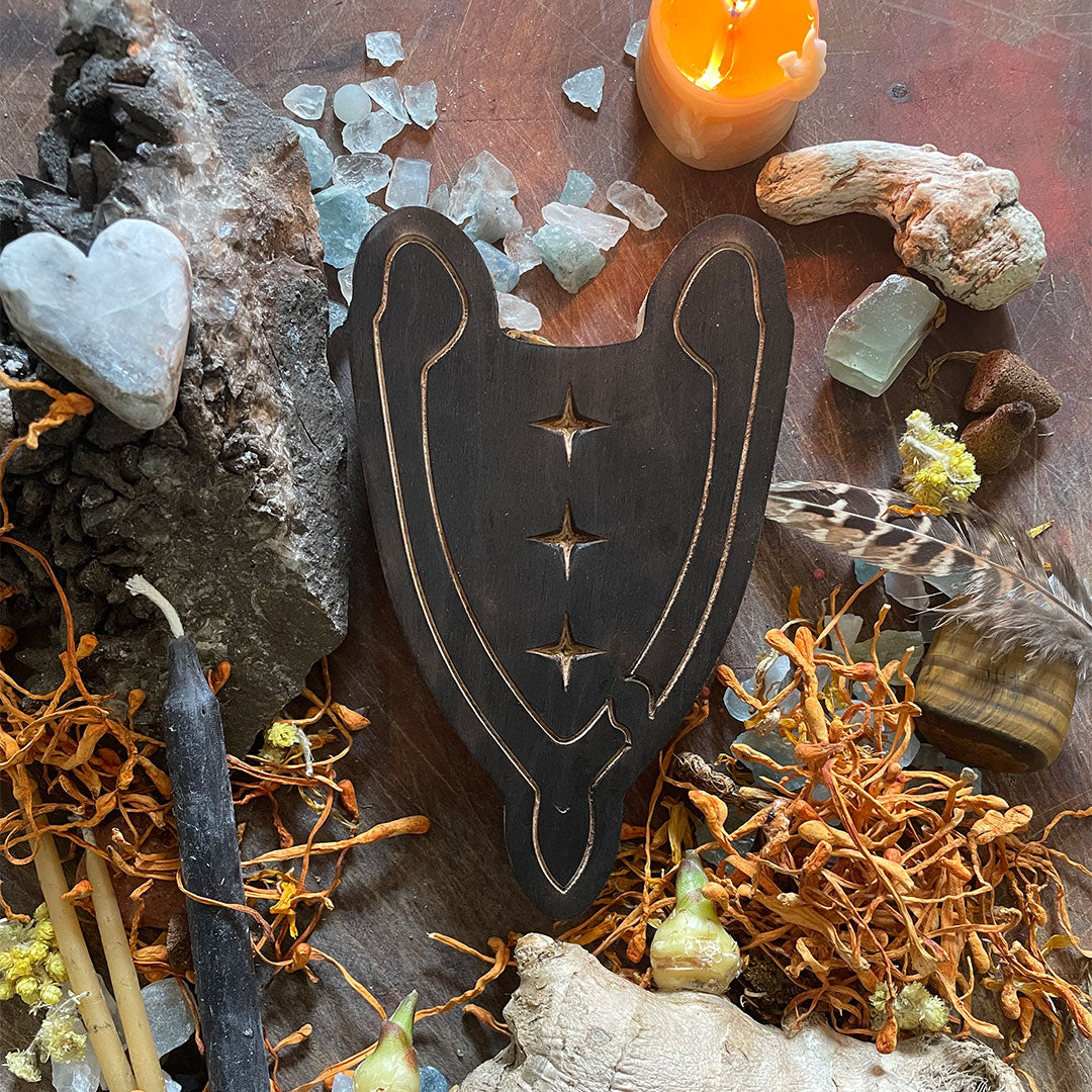 smudged wooden wishbone art therapy project surrounded by dried flowers, crystals, and candles